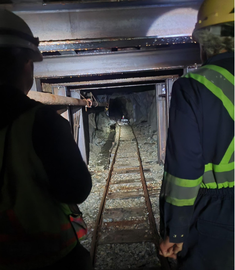 A group of people in hard hats walking through a tunnel<br /> <br /> AI-generated content may be incorrect.