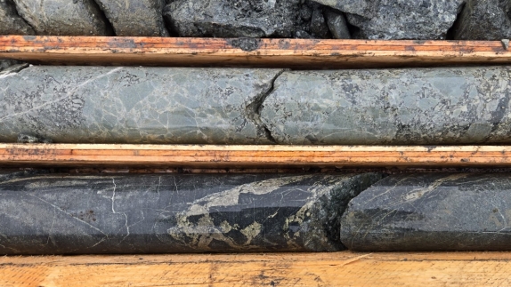 The image shows a close-up view of a collection of black, metamorphic rock slabs with visible layers and a weathered, rough surface.<br /> <br /> AI-generated content may be incorrect.